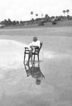Photo for Mahatma Gandhi sitting in a chair at Juhu Beach, Mumbai, Maharashtra, India, May 1944 - Royalty Free Image