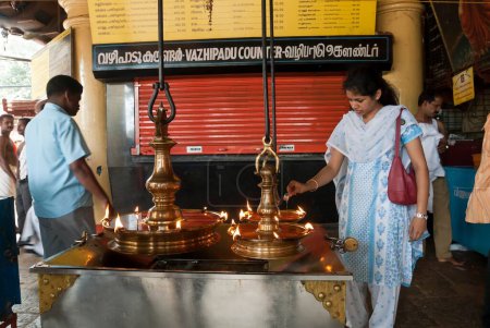 Foto de Mujer vertiendo aceite en diya en kali bhagavathy templo, Kodungallur, Kerala, India - Imagen libre de derechos