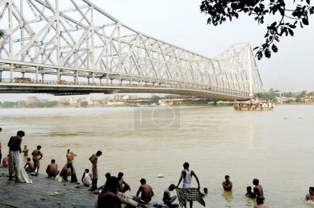 Téléchargez les photos : Les gens se baignent sur le ghat de la rivière Hoostly au pont Howrah (Rabindra Setu), Calcutta maintenant Kolkata, Bengale occidental, Inde - en image libre de droit