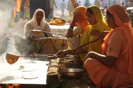 Photo for Sikh devotees making rotis wheat flour bread in community kitchen, Sachkhand Saheb Gurudwara in Nanded, Maharashtra, India - Royalty Free Image