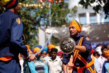 Téléchargez les photos : Guerriers nihang ou sikhs effectuant des cascades avec épée et bouclier pendant les célébrations Hola Mohalla à Anandpur sahib dans le district de Rupnagar, Punjab, Inde - en image libre de droit