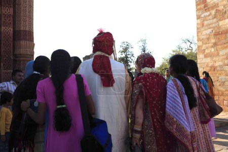 Téléchargez les photos : Les Indiens se sont réunis autour du couple de mariage américain en costume indien dans le complexe Qutb Minar ; Delhi ; Inde Site du patrimoine mondial de l'UNESCO - en image libre de droit