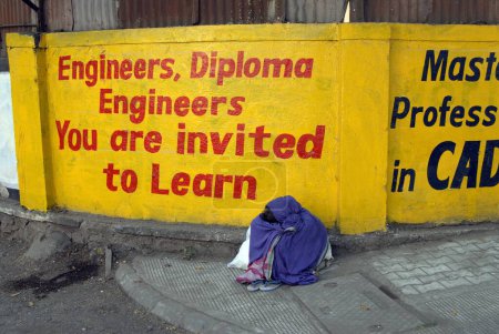 Téléchargez les photos : Une affiche et un mendiant à la gare de Pune, Maharashtra, Inde - en image libre de droit