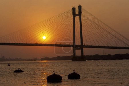 Foto de Vidyasagar Setu (Puente Nuevo Howrah) y amanecer sobre el río Hooghly; Calcuta; Bengala Occidental; India - Imagen libre de derechos