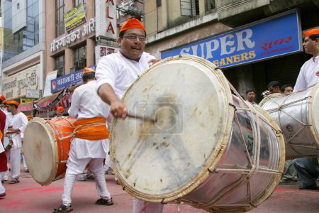Photo for Devotee of Lord Ganesh; the elephant headed God; playing a musical instrument  Dhol on the occasion of the immersion of procession of Lord Ganesh ganpati festival ; Pune ; Maharashtra ; India - Royalty Free Image