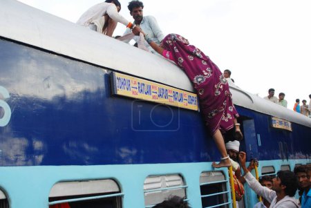 Téléchargez les photos : Hommes traînant vers une femme essayant de monter sur le toit du train à la gare de Jodhpur ; Rajasthan ; Inde - en image libre de droit