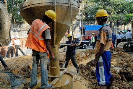 Téléchargez les photos : Les travailleurs remplissent le béton pour ériger un pilier pour 24 km de long survol de Lalbaug sur la route Dr. Ambedkar ; Bombay Mumbai ; Maharashtra ; Inde - en image libre de droit