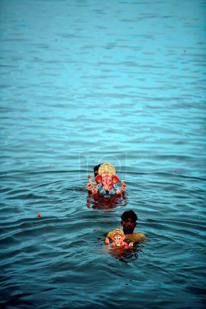 Photo for Idols of Lord Ganesha ganpati Hindu deity being immersed in Powai lake ; Bombay  Mumbai ; Maharashtra ; India - Royalty Free Image