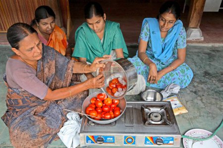 Téléchargez les photos : Des bénévoles de l'ONG Chinmaya Organization of Rural Development CORD montrent comment faire de la sauce tomate dans le cadre d'un programme générateur de revenus, Siruvani, Karnataka, Inde - en image libre de droit