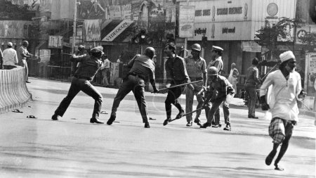 Foto de Policía golpeando a un hombre con palos durante disturbios, Mumbai, Maharashtra, India, Asia, 1900 - Imagen libre de derechos