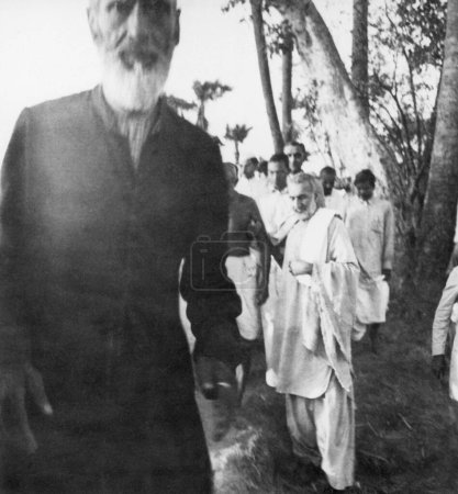 Téléchargez les photos : Mahatma Gandhi ; soutenu par Khan Abdul Gaffar Khan ; et d'autres en marche à travers les zones touchées par les émeutes du Bihar ; 1947 ; Inde - en image libre de droit