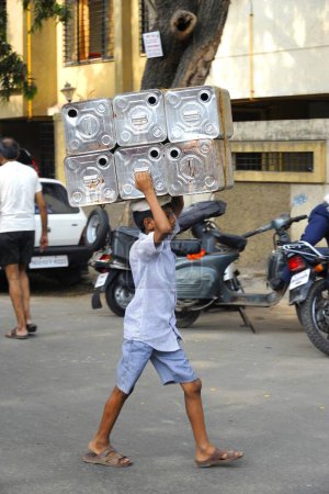 Foto de Niño cargando cajas de estaño, Bombay Mumbai, Maharashtra, India - Imagen libre de derechos