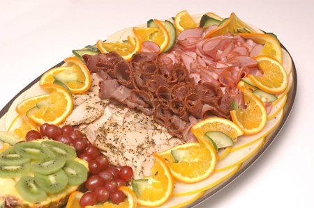 Food , Exotic platter (Cold platter with roast beef , smoked ham and marinated and grilled turkey fillets Platter garnished with pineapple head , honeydew melon , kiwi , black grapes , sweet lime and cucumber twist)