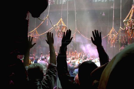 Foto de Devotos levantando sus manos como marca de rendición total al Señor Krishna, celebraciones del festival Holi en el templo Banke Bihari, Vrindavan, Uttar Pradesh, India - Imagen libre de derechos