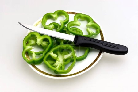 Foto de Rodajas de Capsicums verdes Capsicum annuum latino en un plato con cuchillo, ensalada, India - Imagen libre de derechos