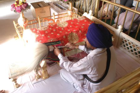 Téléchargez les photos : Homme lisant Adigranth ; Akaltakhat Golden temple, Amritsar, Punjab, Inde - en image libre de droit