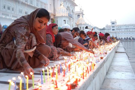 Photo for Devotees lighting candles on the pomegranates of the Golden Temple also known as Harimandir Granth Sahib ; sacred place of worship of Sikhs at Amritsar ; Punjab ; India on the occasion of birth anniversary of first Sikh Guru Sri Guru Nanak Dev ji dur - Royalty Free Image