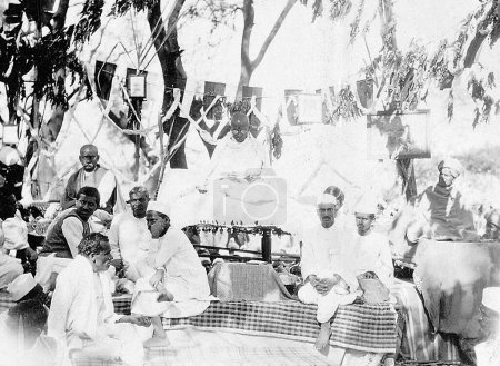 Téléchargez les photos : Mahatma Gandhi jouant de son instrument takli spinning lors d'une réunion publique 1929 - en image libre de droit