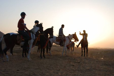 Foto de Entrenador de caballos y turistas en silueta, feria de Pushkar, Rajastán, India - Imagen libre de derechos