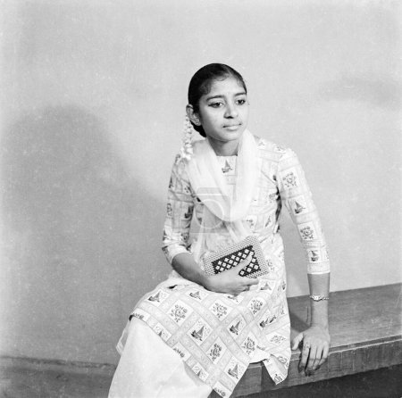 Photo for Old vintage 1900s black and white studio picture of Indian girl wearing salwar kameez purse hand hair flower India - Royalty Free Image