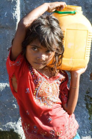 Foto de Niña llevando agua en el tugurio de Malvani, Malad, Bombay Mumbai, Maharashtra, India - Imagen libre de derechos