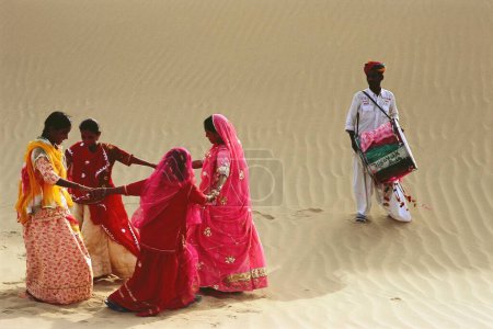 Téléchargez les photos : Danse folklorique, femmes rajasthanes dansant et homme jouant du tambour dans le sable, Khuhri, Jaisalmer, Rajasthan, Inde - en image libre de droit