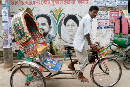 Foto de Ciclo Rickshaw Rider Pasando Cerca de la Pared Pintura de Graffiti Político; Daca; Bangladesh - Imagen libre de derechos