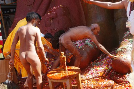 Téléchargez les photos : Nu Jain sadhu toucher pieds de 57 pieds de haut statue du seigneur Bahubali connu sous le nom Gomateshvara dans Mahamasthakabisheka célébration à Sravanabelagola dans le district de Hassan du Karnataka, Inde - en image libre de droit