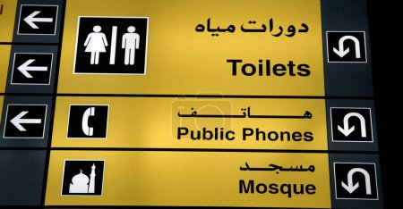 Photo for Yellow sign board of toilet public phones mosque at Dubai International Airport, Dubai Middle East UAE United Arab Emirates - Royalty Free Image