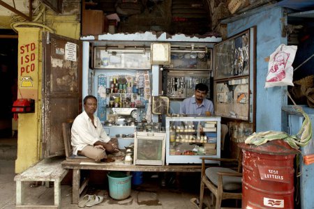 Photo for A small niche along an entrance of a building is creatively used by twin professionals - a watch repairer and a paan (beetle leaf) seller ; Both the shops are sandwiched between a letter box and a public phone booth ;  Mumbai Bombay ; Maharashtra ; - Royalty Free Image