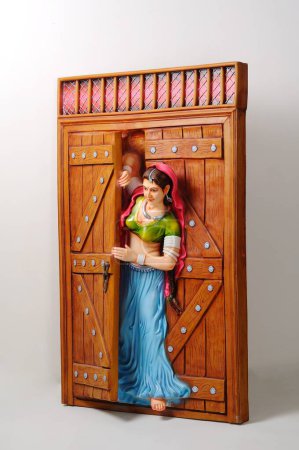 Figura de arcilla, estatua de niña rajasthani asomándose por la puerta medio abierta