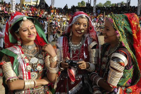 Foto de Chicas en joyería tradicional y traje de rajasthani tener charla entre sí, feria de Pushkar, Rajastán, India - Imagen libre de derechos