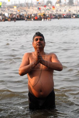 Téléchargez les photos : Un dévot prie au confluent du Gange, Yamuna les mythiques rivières Saraswati de prendre un bain sacré pendant l'Ardh Kumbh Mela, Inde - en image libre de droit
