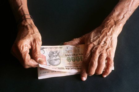 Téléchargez les photos : Une vieille femme tenant de l'argent, billets, roupies, monnaie indienne - en image libre de droit