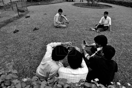 Photo for Boys mobile phones, Pherozeshah Mehta Garden, Hanging Garden, Malabar Hill, Mumbai, Maharashtra, India, Asia - Royalty Free Image
