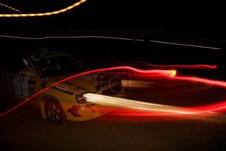 Téléchargez les photos : Séries de feux avant et arrière de voitures et de lampadaires en excès de vitesse la nuit dans la course tenue au complexe sportif Balewadi, Pune, Maharashtra, Inde - en image libre de droit