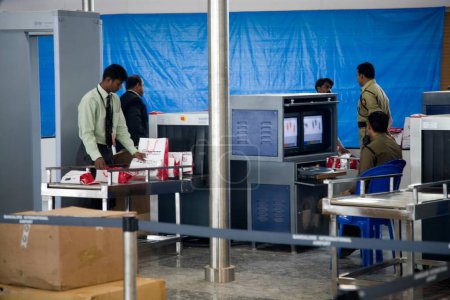 Téléchargez les photos : Contrôle de sécurité, agents de service scannant les bagages à travers les moniteurs, aéroport international de Bengaluru, Bangalore, Karnataka, Inde - en image libre de droit