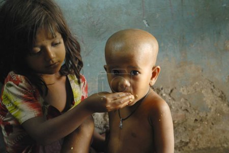 Téléchargez les photos : Fille nourrissant frère cadet, Bombay Mumbai, Maharashtra, Inde - en image libre de droit