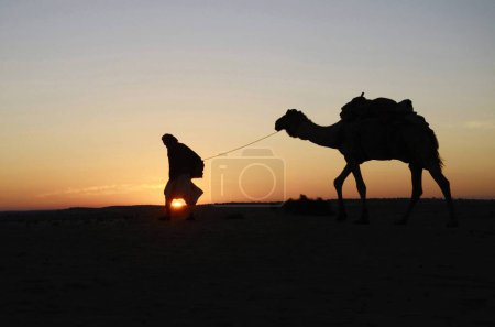 Téléchargez les photos : Homme avec chameau l marche sur les dunes de sable Khuhri à Jaisalmer Rajasthan Inde - en image libre de droit