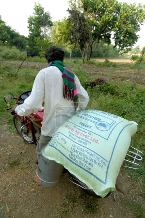 Téléchargez les photos : Homme à vélo avec des aliments pour bétail achetés de la laiterie ; Ralegaon Siddhi ; près de Pune ; Maharashtra ; Inde - en image libre de droit