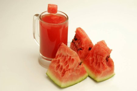 Fruits ; A glass of watermelon juice and three cut pieces showing red watery pulp and black seeds ; Pune; Maharashtra; India