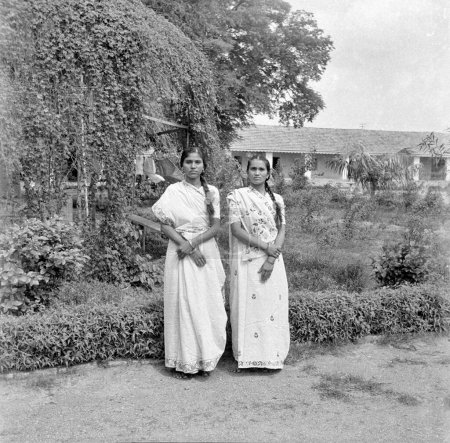 Photo for Old vintage 1900s black and white picture of Indian twin sisters portrait wearing saris garden India 1940s - Royalty Free Image