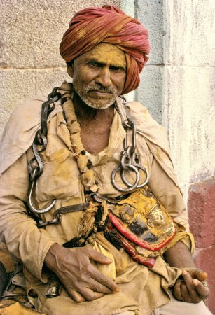 Photo for Khandobas devotee with face smeared with yellow turmeric powder and heavy metal chain round their neck, Jejuri, Maharashtra, India - Royalty Free Image