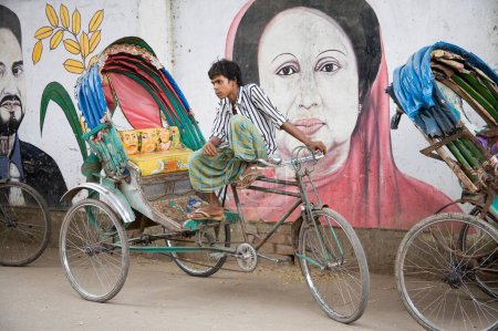 Téléchargez les photos : Extracteur Rickshaw attendant le passager près de la peinture murale du politicien Begum Khalida Zia ; Old Dhaka ; Bangladesh - en image libre de droit