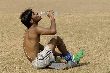 Téléchargez les photos : Athlète indien boire de l'eau dans l'aire de jeux - en image libre de droit