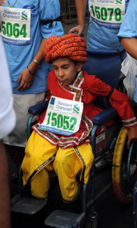 Téléchargez les photos : Participant handicapé en fauteuil roulant garçon en robe fantaisie à Marathon, Mumbai, Maharashtra Inde - en image libre de droit