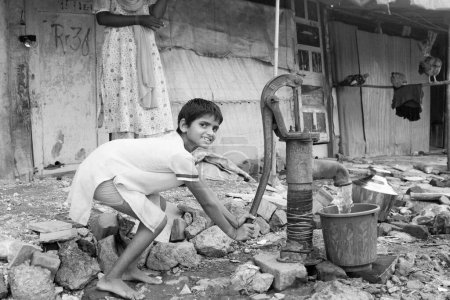 Photo for Girl pumping water from hand pump ; Malvani slum ; Malad ; Bombay Mumbai ; Maharashtra ; India - Royalty Free Image