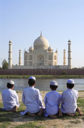 Photo for Young muslim boys performing religious prayer Namaz in front of Taj Mahal Seventh Wonders of World on south bank of Yamuna river , Agra , Uttar Pradesh , India UNESCO World Heritage Site - Royalty Free Image
