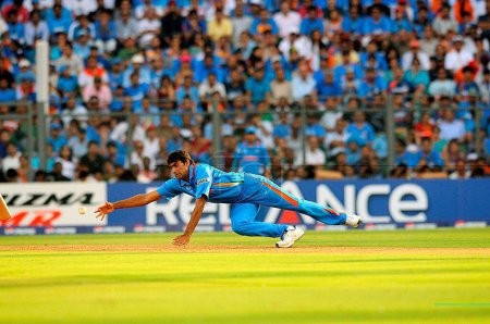 Téléchargez les photos : Le joueur indien Munaf Patel plonge pour arrêter le ballon lors de la finale de la Coupe du monde de cricket ICC contre Sri Lanka au stade Wankhede à Mumbai le 02 avril 2011 - en image libre de droit
