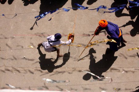 Foto de Guerreros nihang o sij realizando acrobacias con espadas de madera durante las celebraciones de Hola Mohalla en el sahib de Anandpur en el distrito de Rupnagar, Punjab, India - Imagen libre de derechos